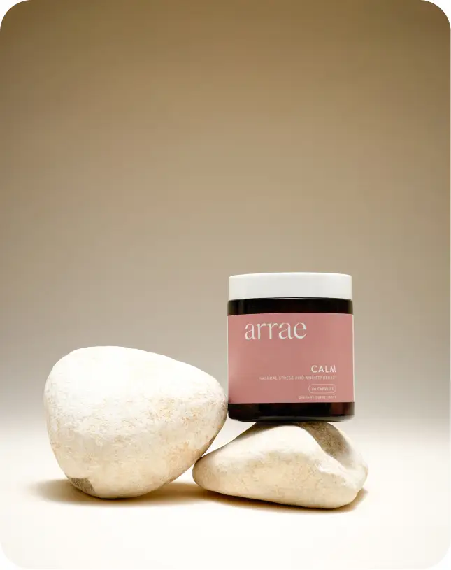 Herbal supplement jar labeled 'Calm' with stones against a beige background.