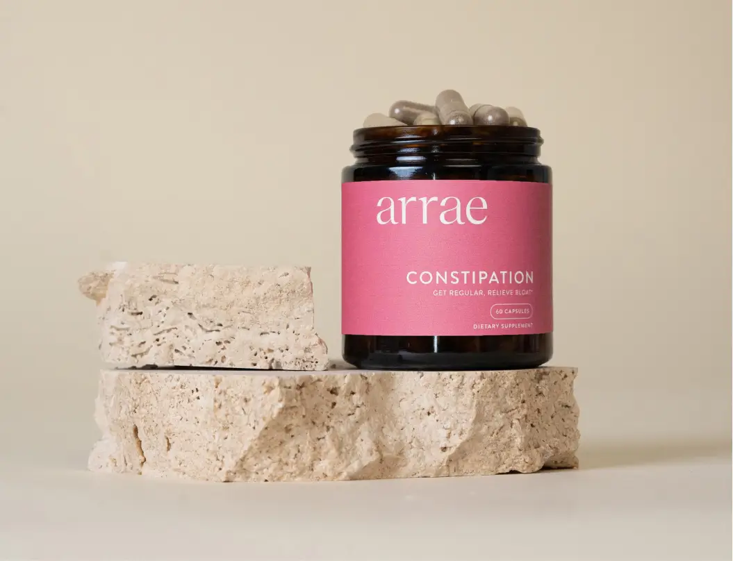 Glass jar with a pink label on rough stone blocks.