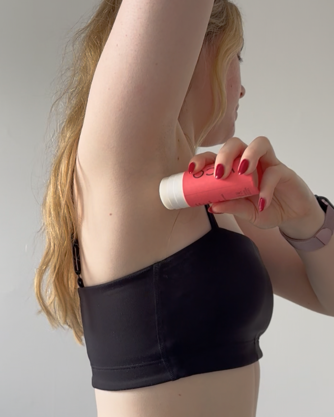 Person applying deodorant to their underarm.