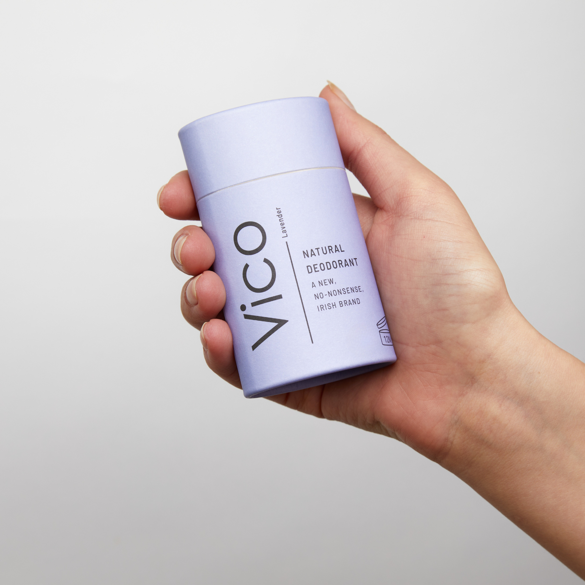 Hand holding a lavender-colored natural deodorant stick.