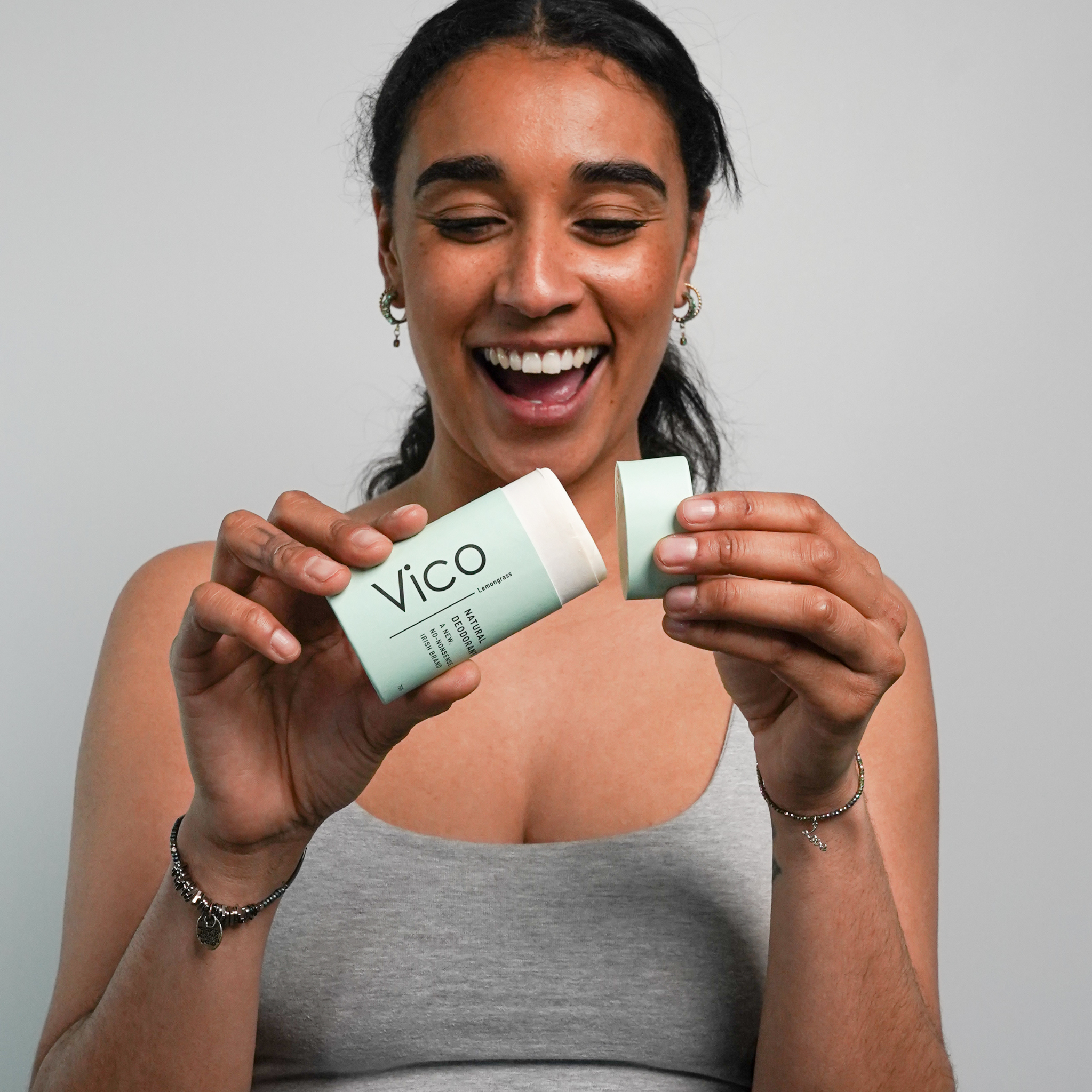 Person smiling while holding a Vico deodorant stick.