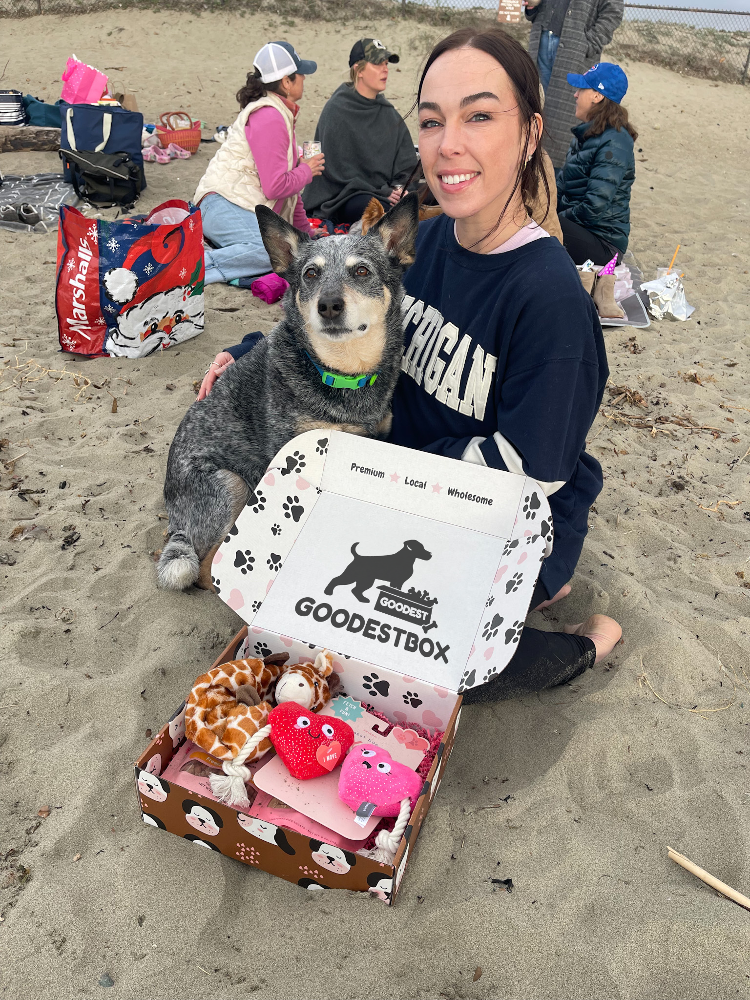 Woman and dog at a beach with a Goodest Box of toys.