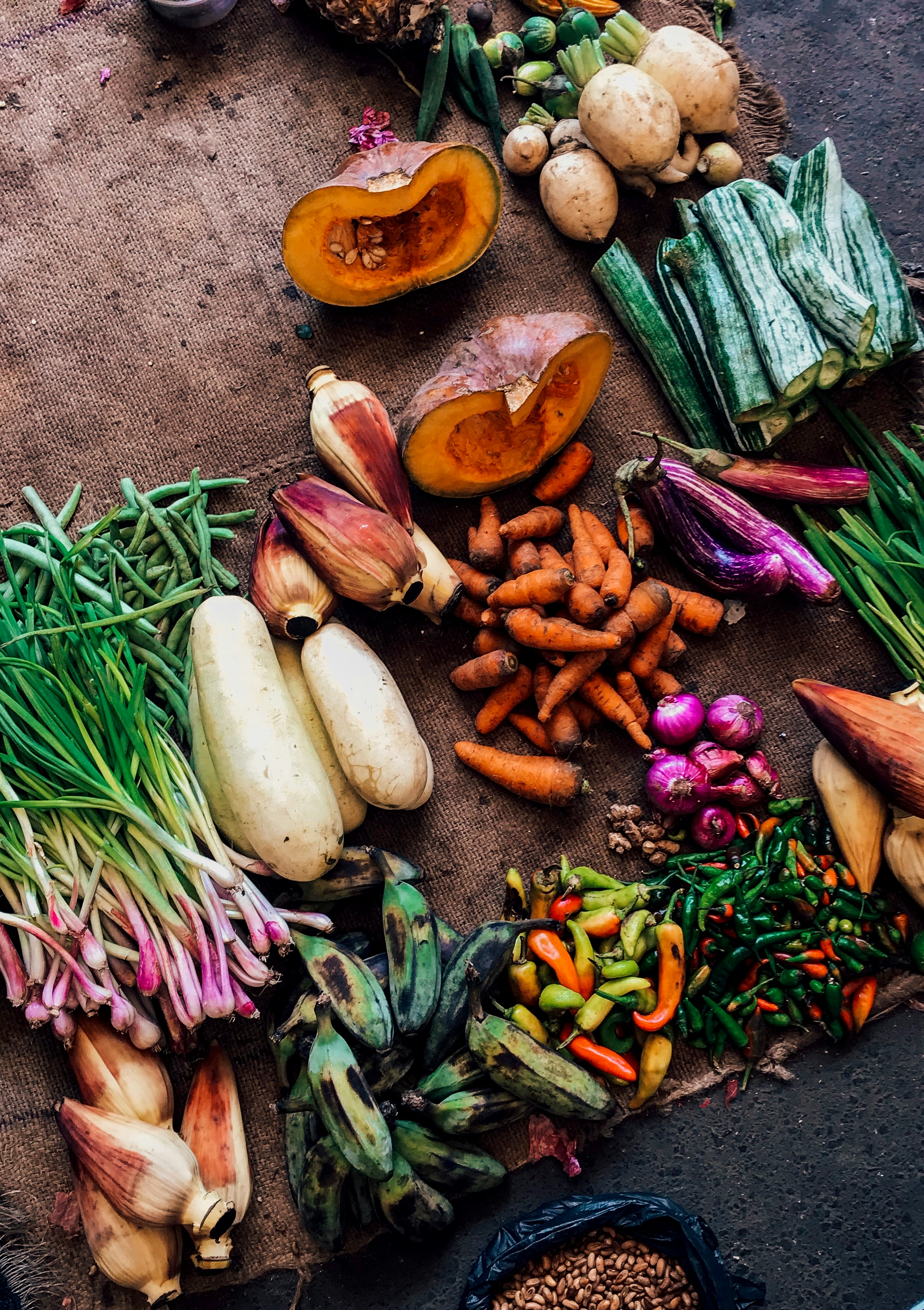Assorted vegetables and fruits on a burlap surface.