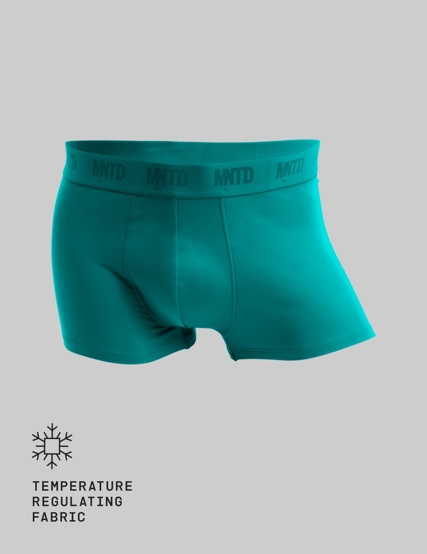 A pair of teal men's boxer briefs with the MNTD logo on the waistband against a gray background.