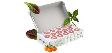 An open 'Eat Healthy' box of plant pods, surrounded by basil, lettuce, and cherry tomatoes.