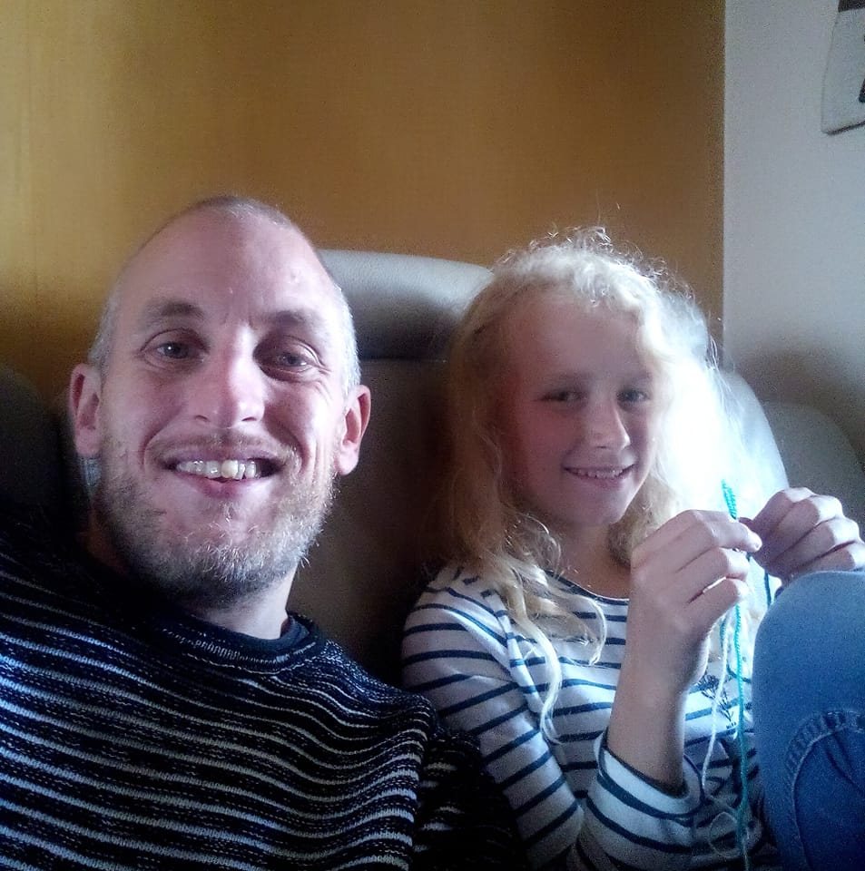 A person and a child smiling while sitting on a couch.
