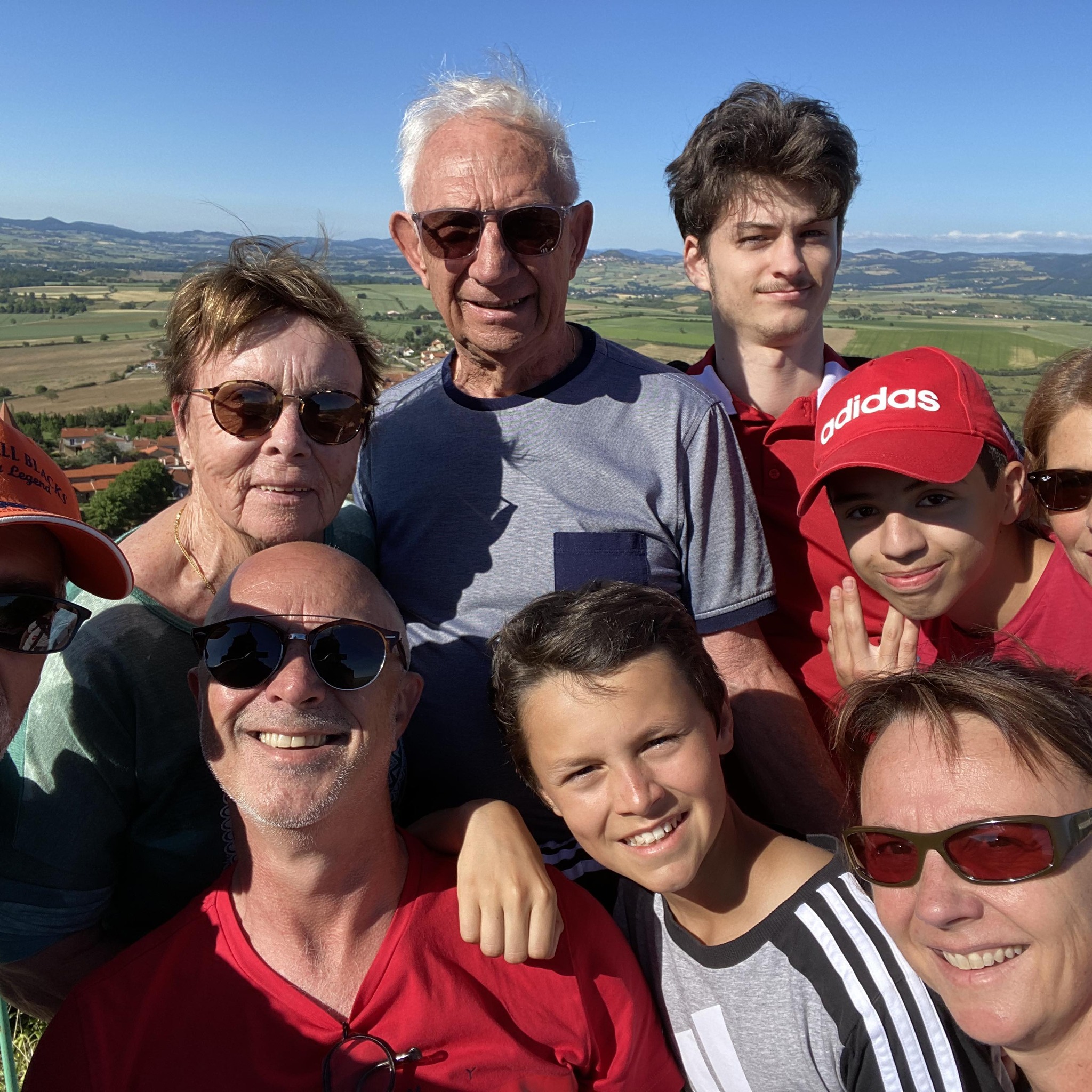 A group of people poses outdoors with a scenic landscape in the background.