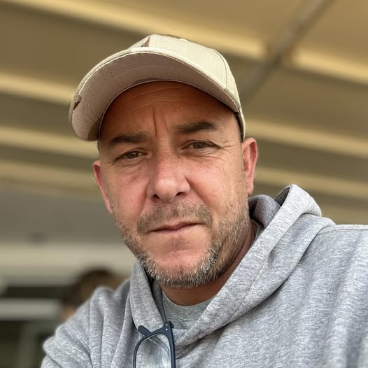 A person wearing a cap and hoodie, looking at the camera.