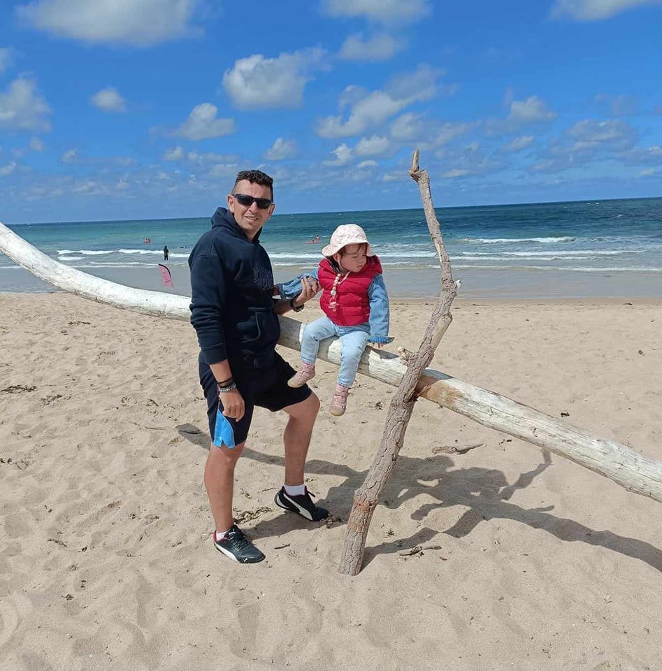Man and child on beach with driftwood.