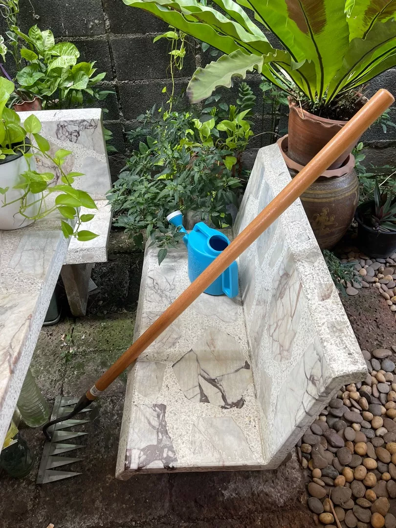 Garden tools and plants arranged on stone benches outdoors.