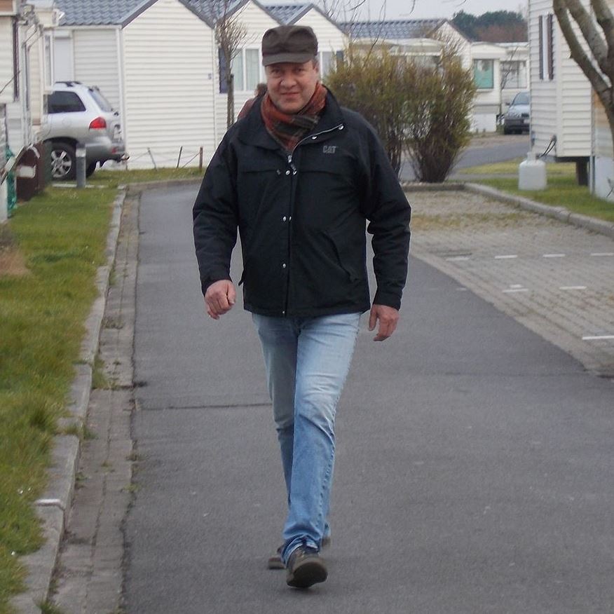 Man walking down a residential street on a cold day.