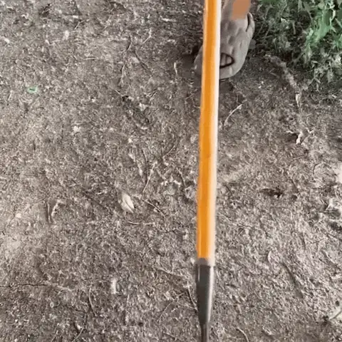 A person using a metal detector on a dirt surface.