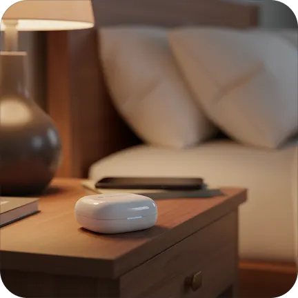 Nightstand with a lamp, wireless earbuds case, and a smartphone.