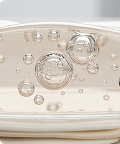 A close-up macro shot of bubbles of various sizes suspended in a clear, pale yellow liquid.