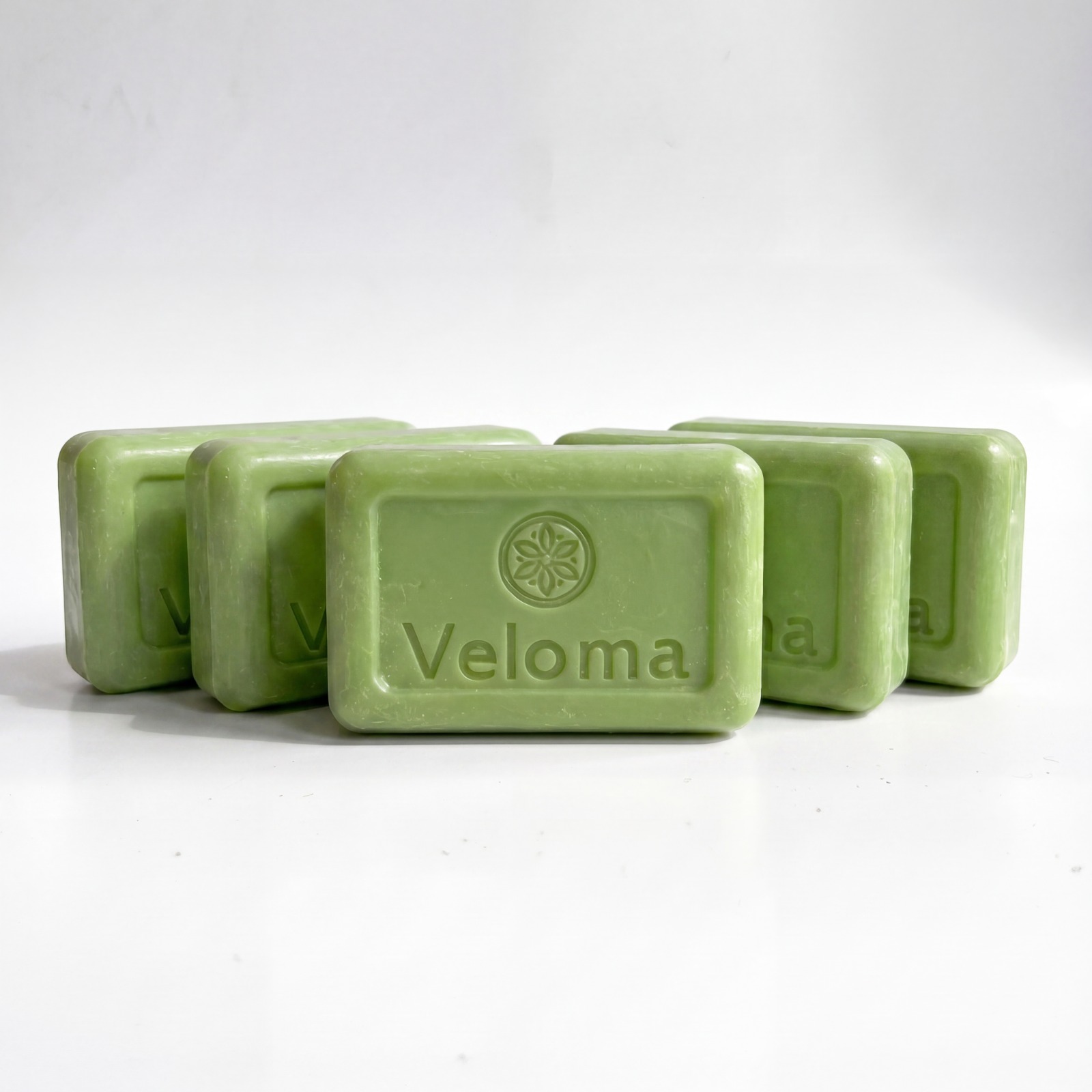Five rectangular bars of light green Veloma brand soap arranged on a white surface.