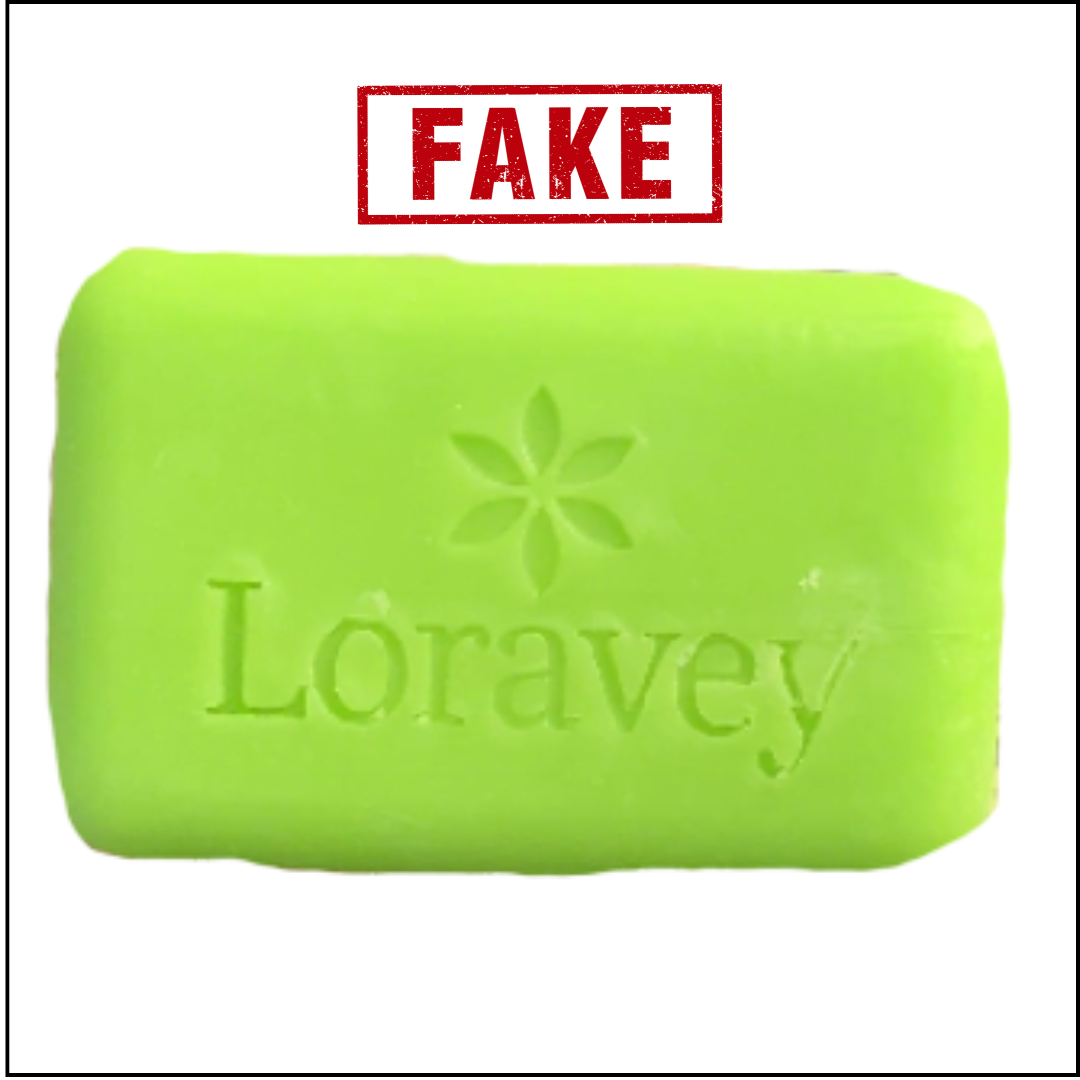 A light green bar of soap with 'Loravey' embossed on it, stamped with the word 'FAKE'.
