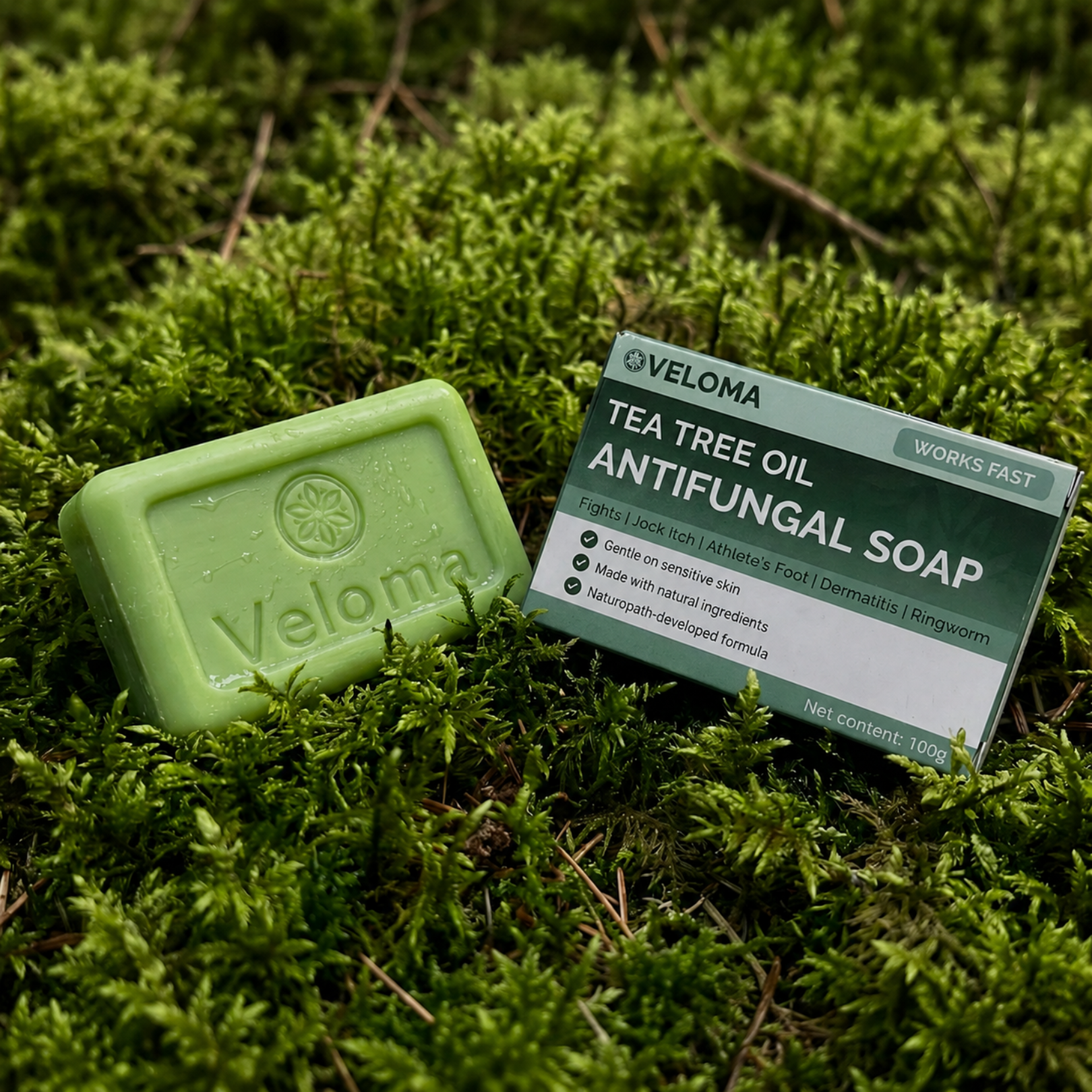 A bar of Veloma Tea Tree Oil Antifungal Soap and its box resting on a bed of green moss.
