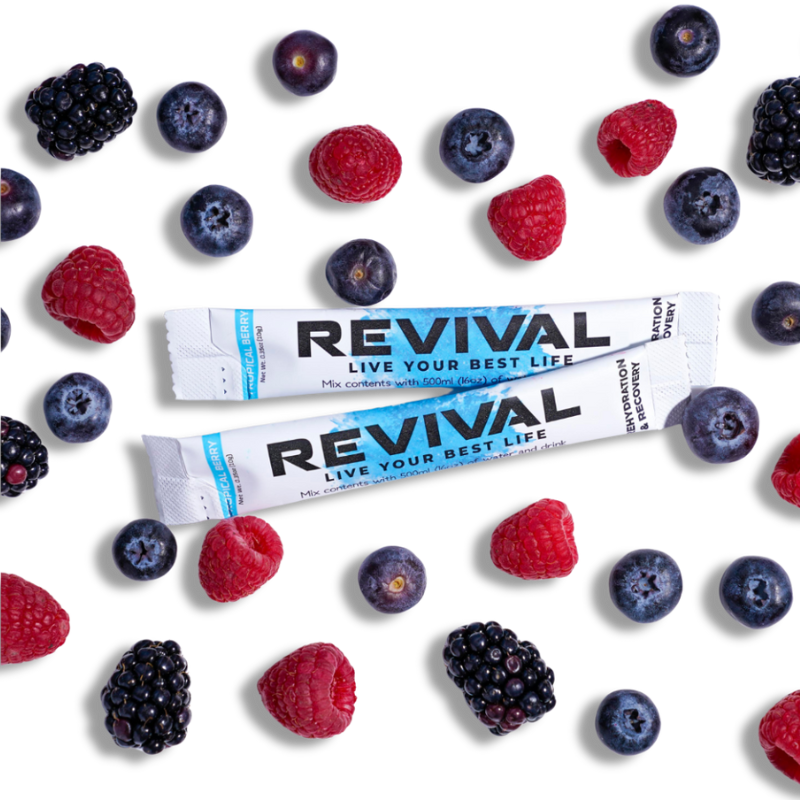 Two Revival packets surrounded by assorted berries on a black background.