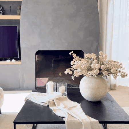 Modern living room with a large vase of flowers on a black coffee table.