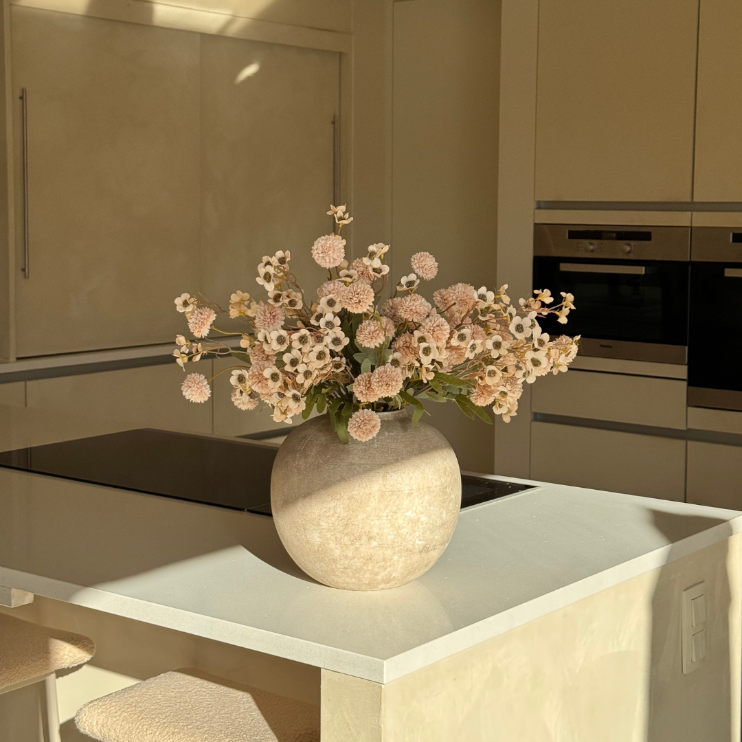 Vase with pink flowers on a kitchen counter.