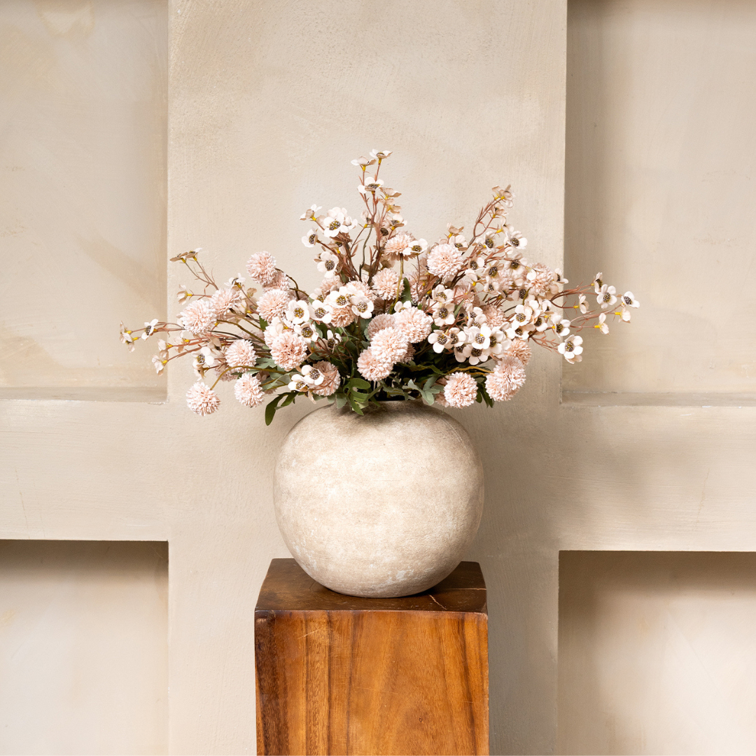 White vase with pink and white flowers on a wooden pedestal.