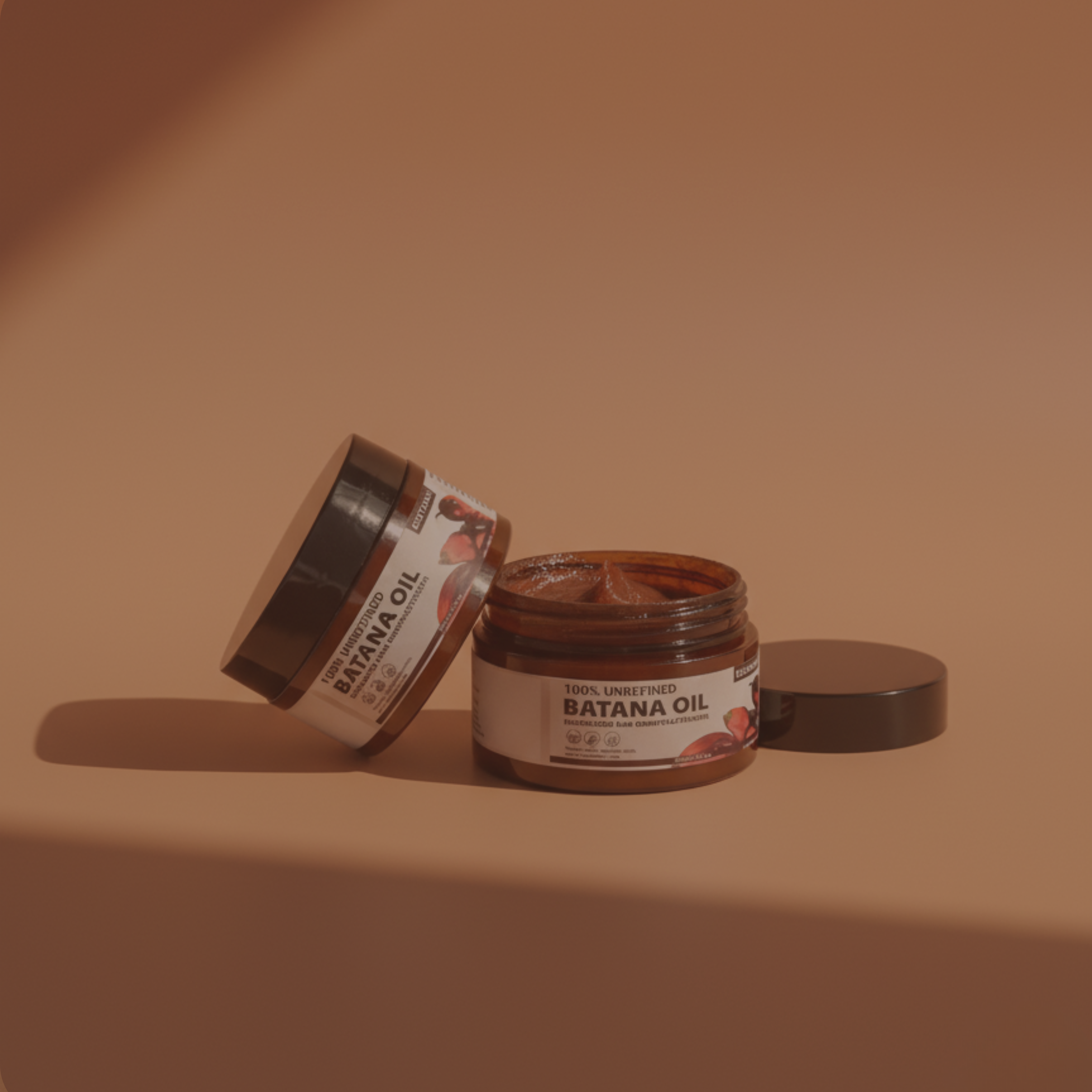 Two jars of 100% Unrefined Batana Oil on a brown background, one open and the other tilted.