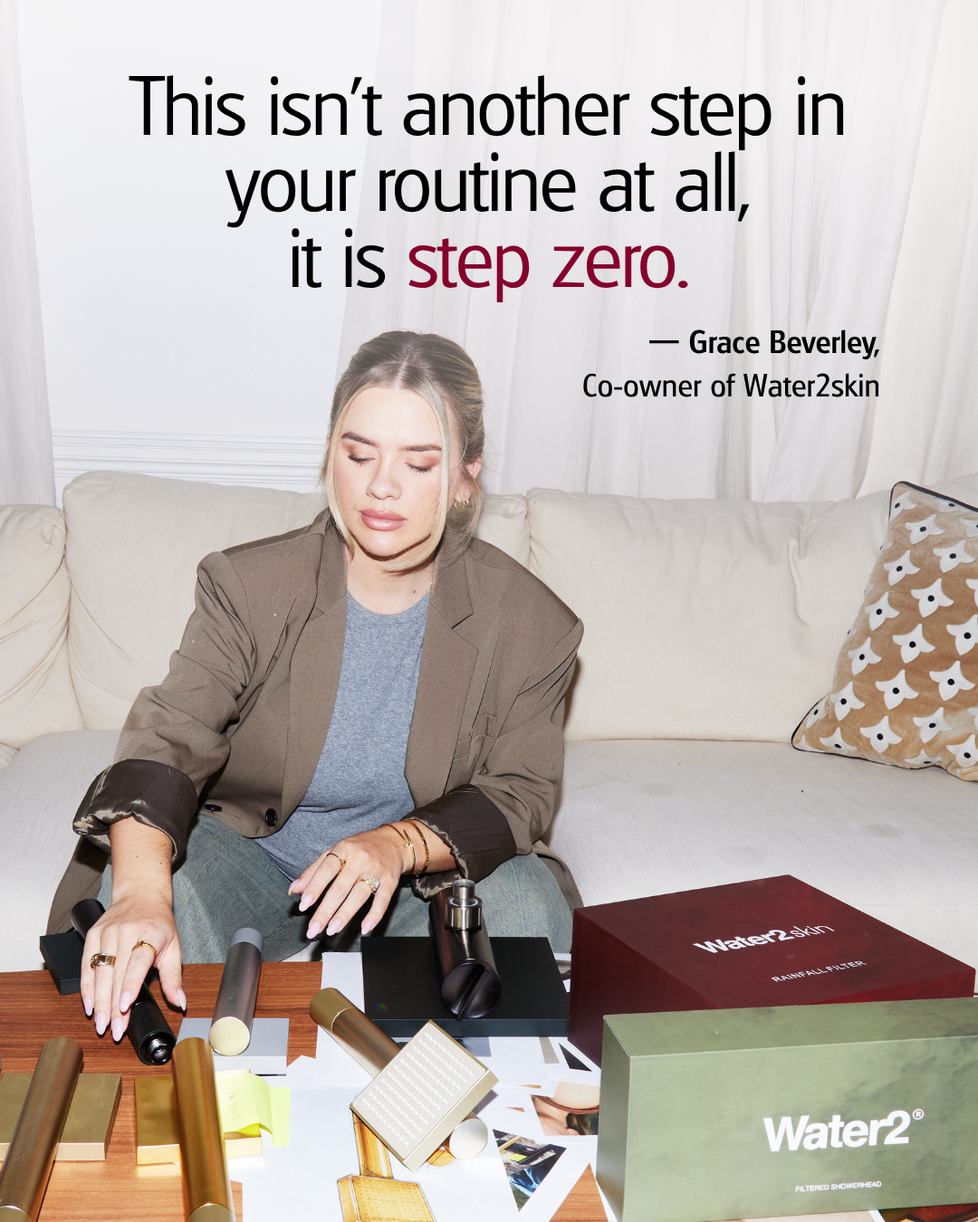 Grace Beverley sits on a couch, looking down at Water2skin products on a coffee table.
