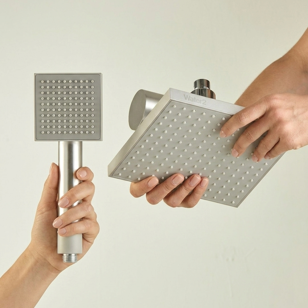 Two people holding a square handheld shower wand and a larger square fixed rain shower head.