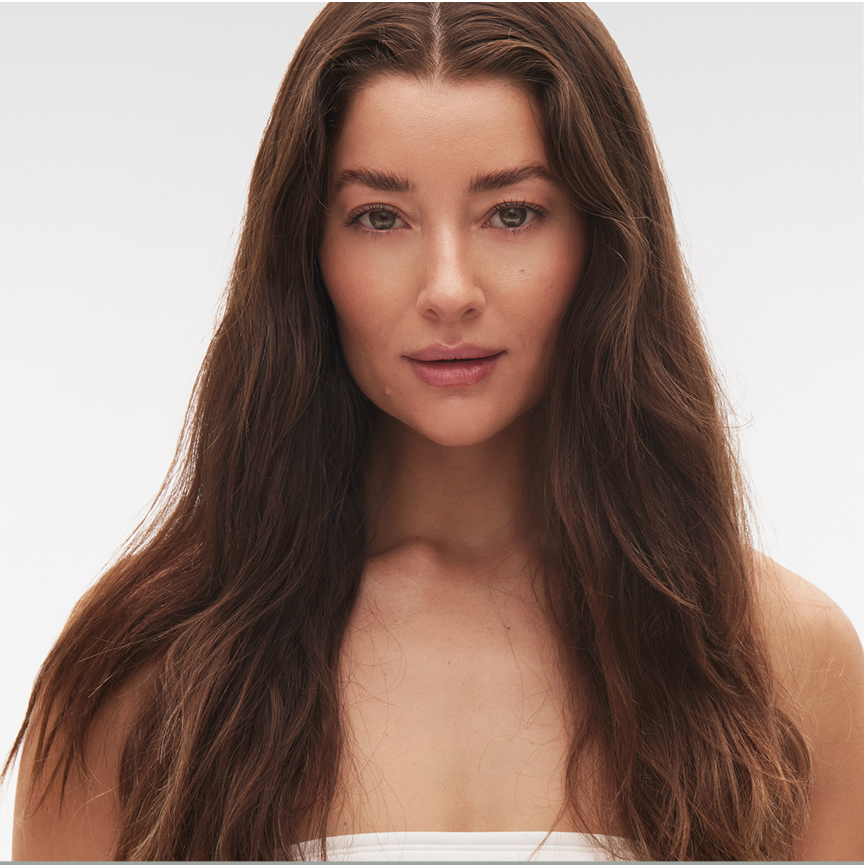 Woman with long brown hair and neutral expression against a plain background.