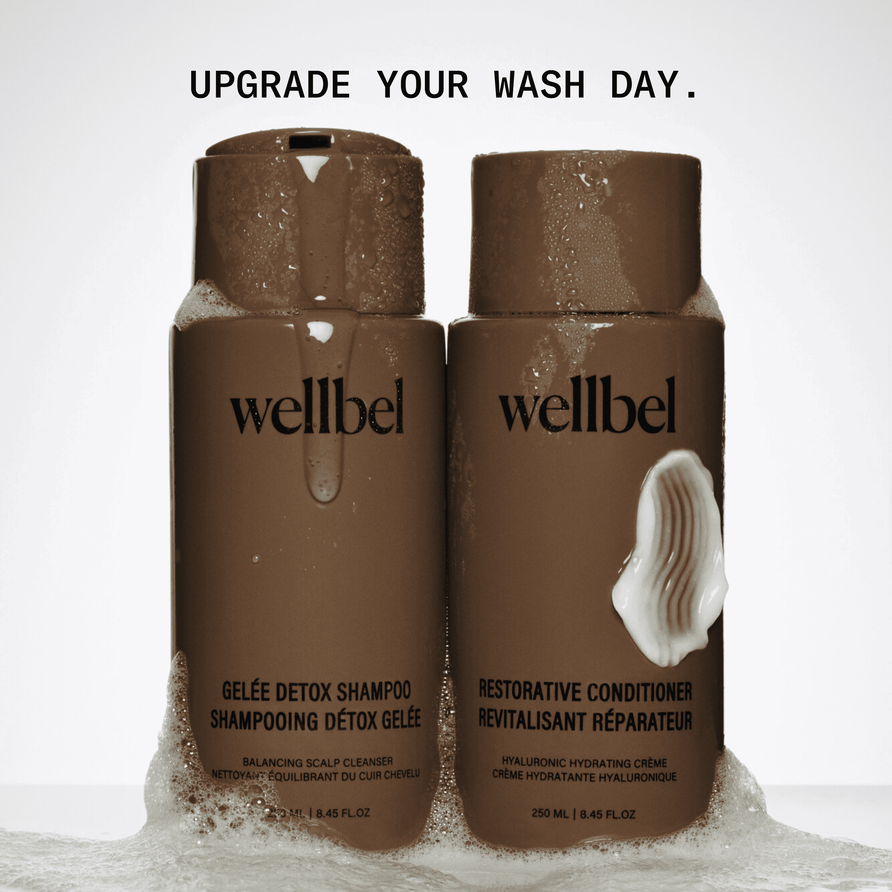 Two brown bottles of Wellbel shampoo and conditioner with foam and text above.