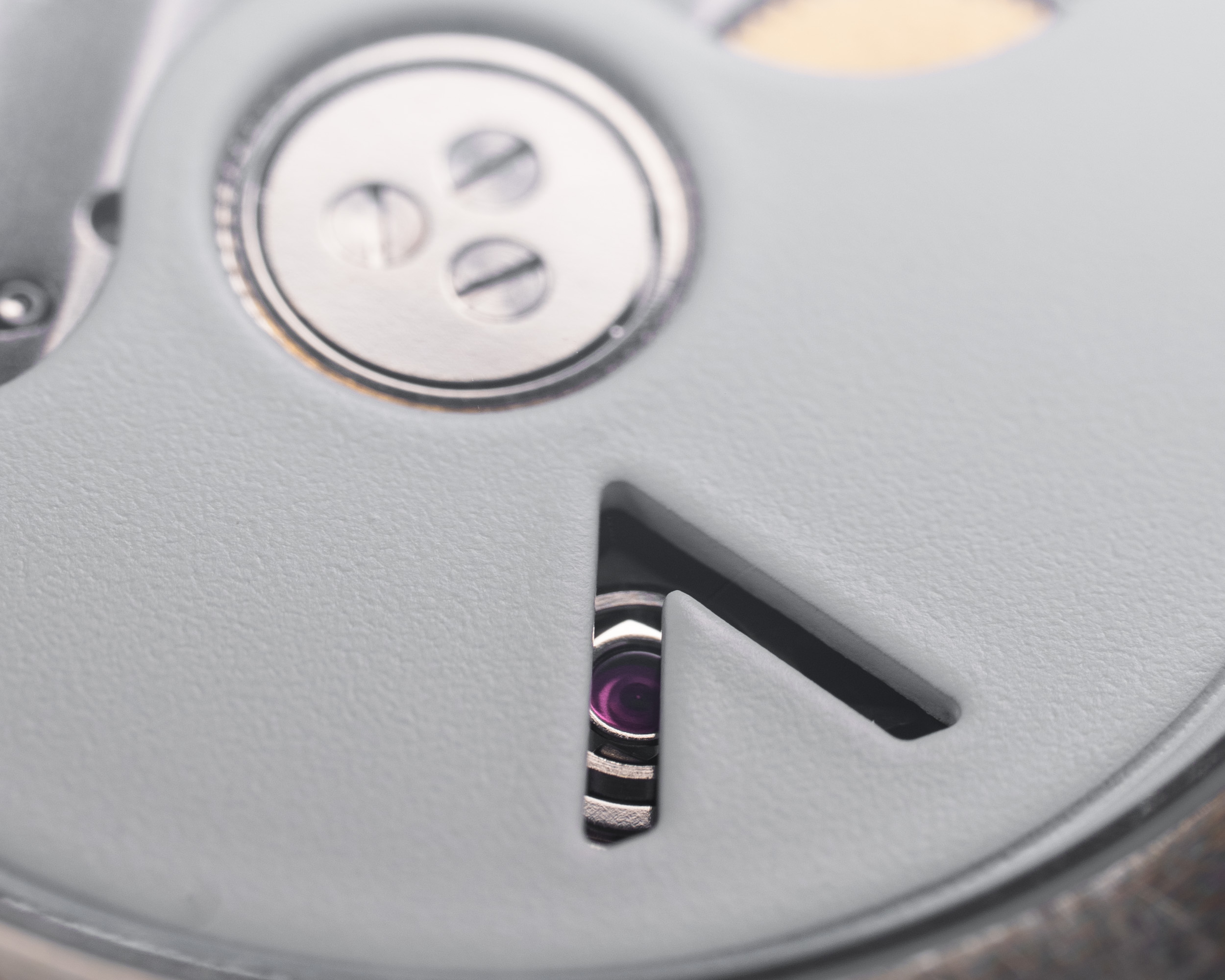 A macro close-up of the inner workings of a watch, showing a jewel through a cut-out.