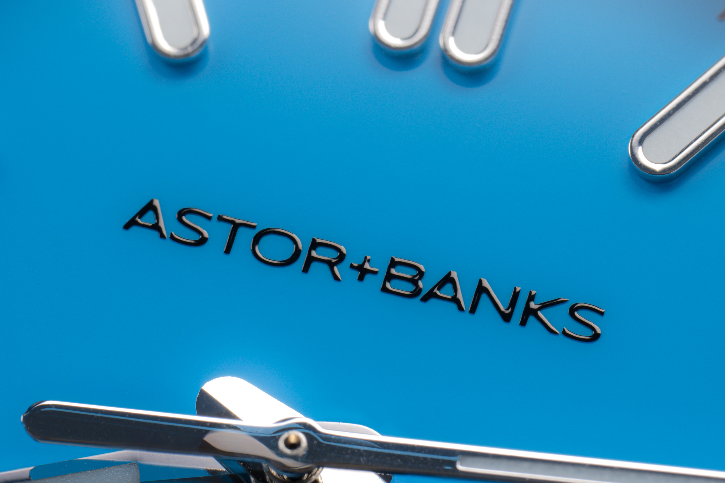 A close-up macro shot of a bright blue watch face with the brand name Astor+Banks.