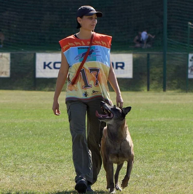 Person walking with a dog on a grassy field.