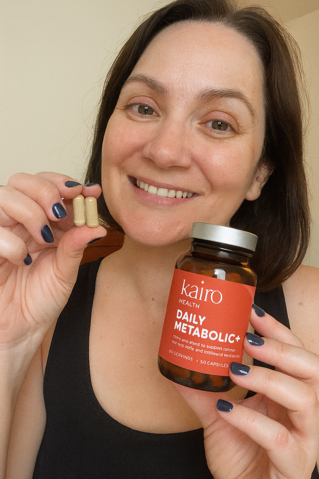 Person holding a bottle of Kairo Health Daily Metabolic+ and two capsules.