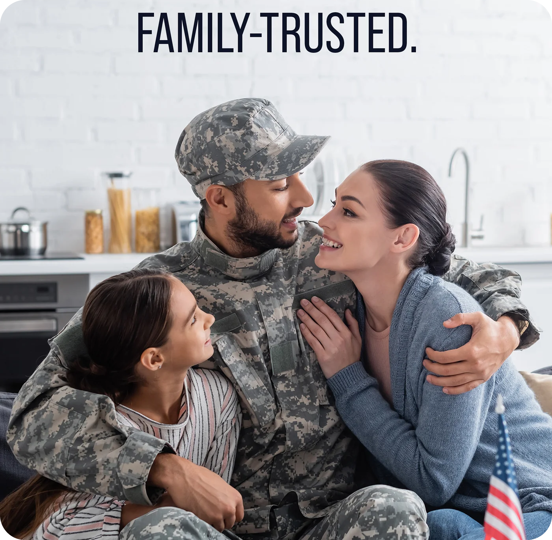 A soldier hugging a woman and a girl in a kitchen with 'Family-Trusted.' text above.