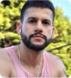 A man with a beard wearing a pink tank top outdoors.