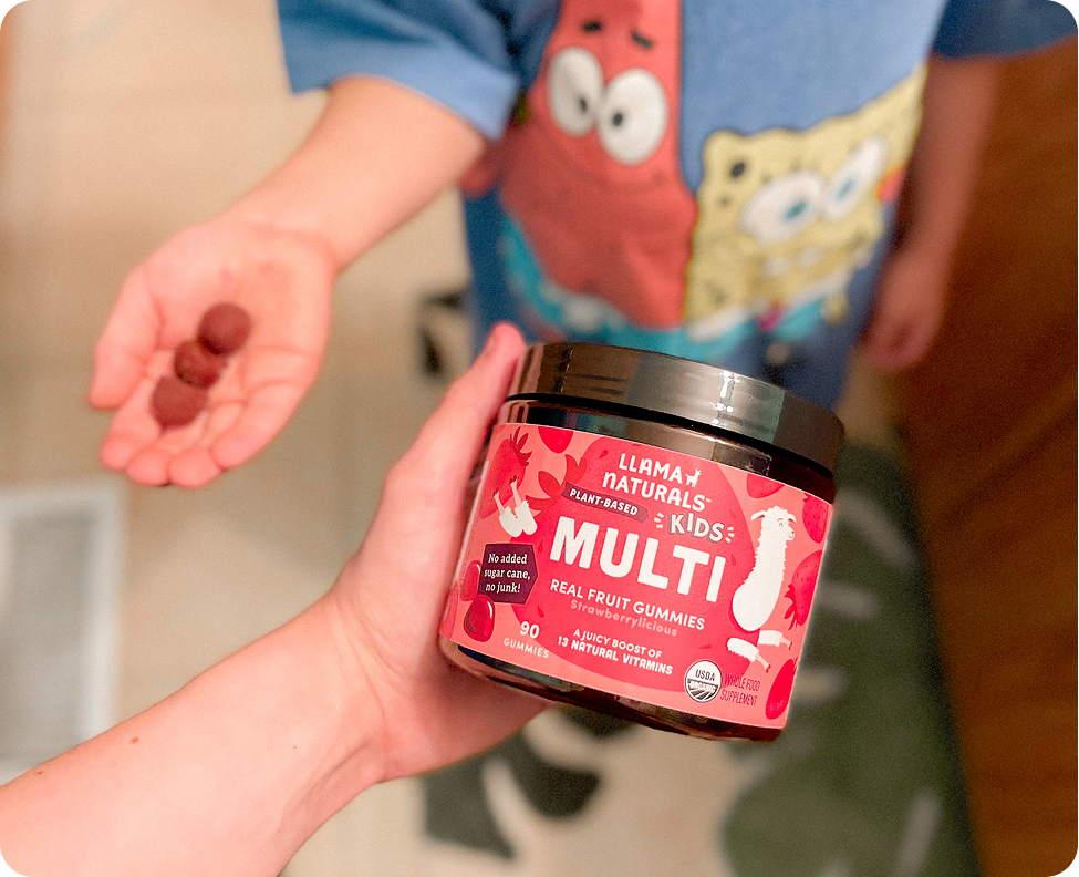 A person holds a jar of Llama Naturals Kids Multi gummies while a child holds some in their hand.