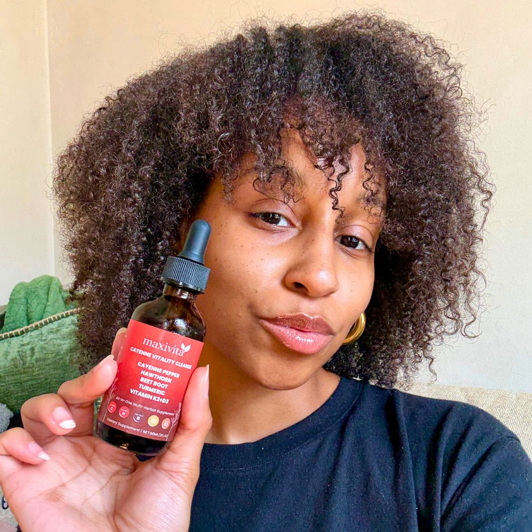 Person holding a bottle labeled 'maxivita' with a dropper cap.