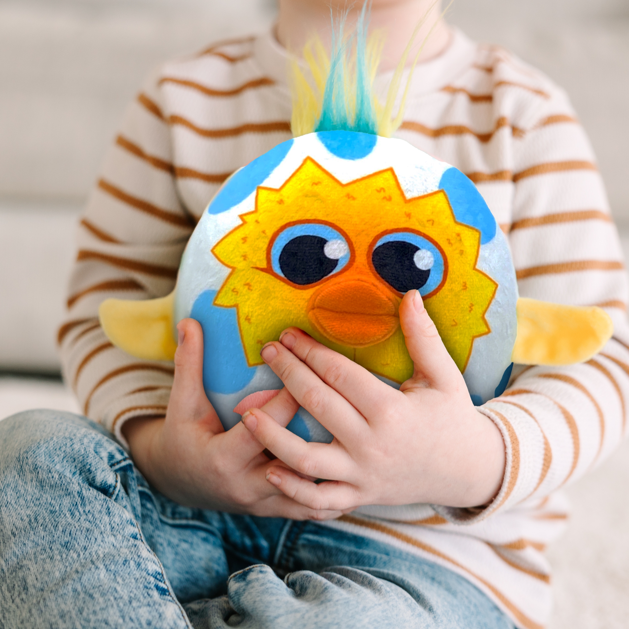 Child hugging a colorful, round plush toy with big eyes.