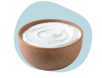Wooden bowl filled with white creamy yogurt on a light blue background.