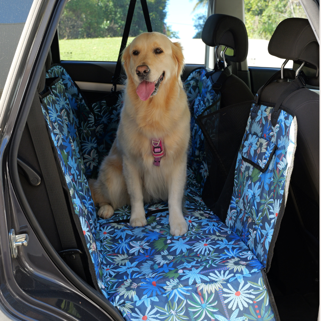 Golden retriever sitting on floral car seat cover.