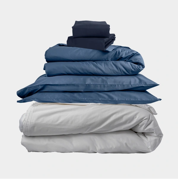 Stack of folded blue and grey bedding on a white background.