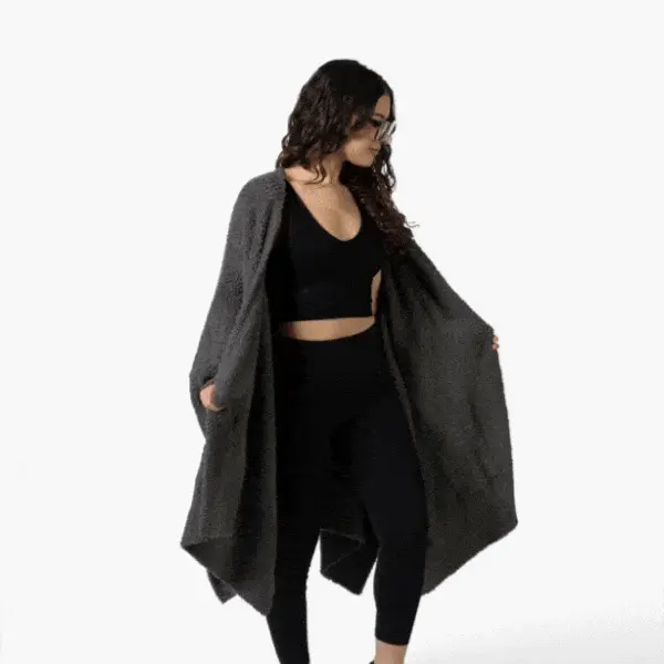 Person wearing a black outfit and gray shawl, standing against a white background.