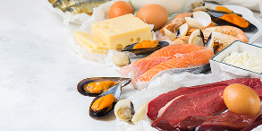 Assorted seafood, cheese, eggs, and meat on a white surface.