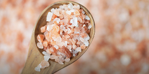 Wooden spoon filled with pink Himalayan salt crystals.