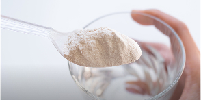 Spoon with white powder over a glass of water.