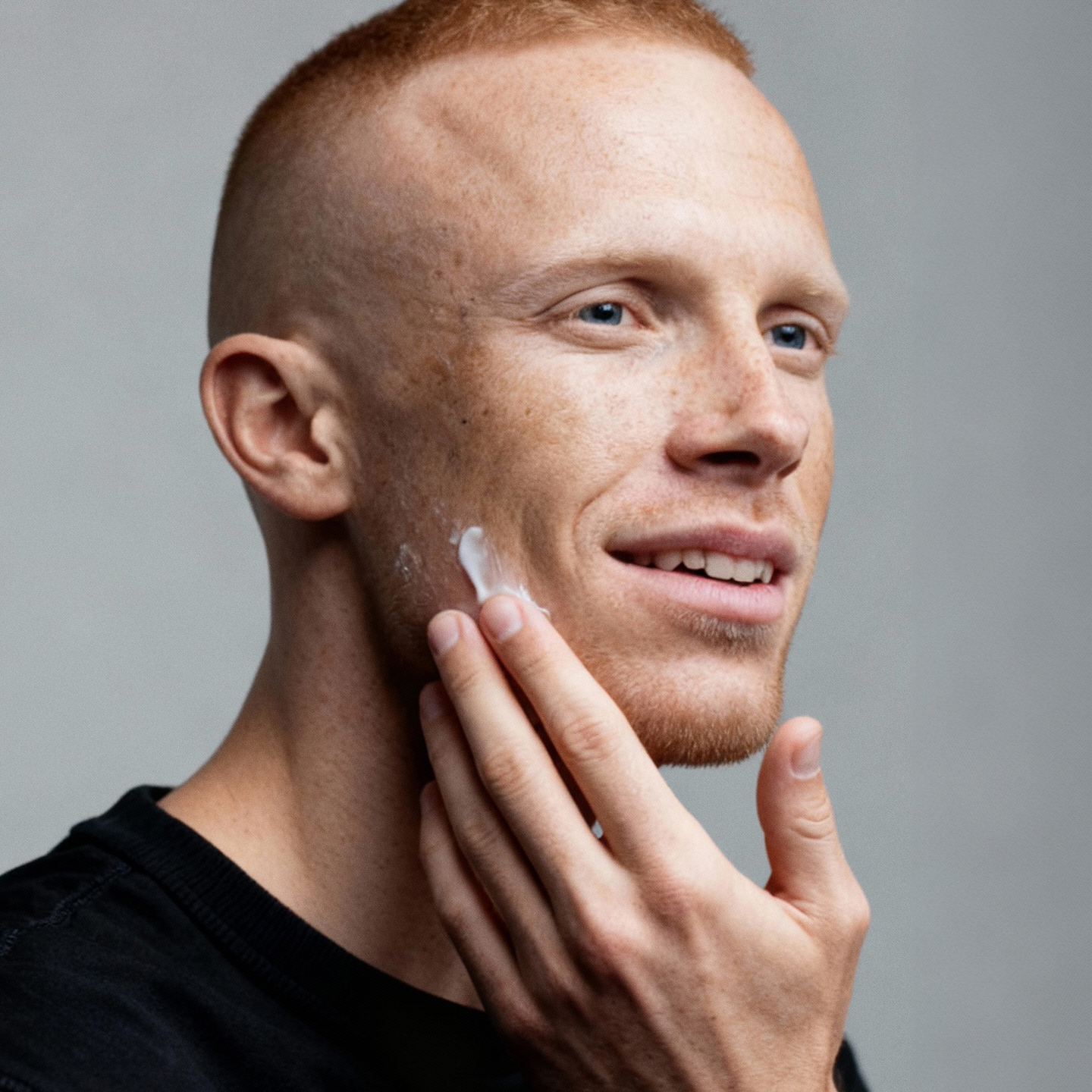 Person applying cream to their cheek with a hand.