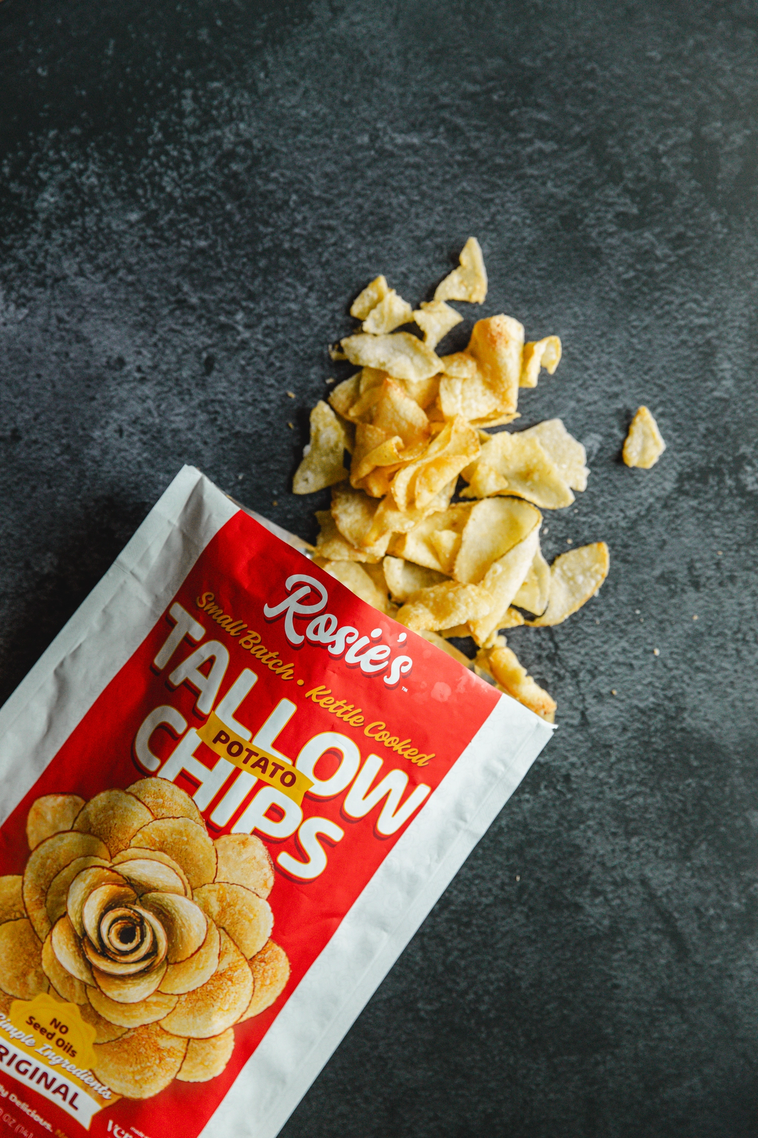 Bag of potato chips spilling onto a dark surface.