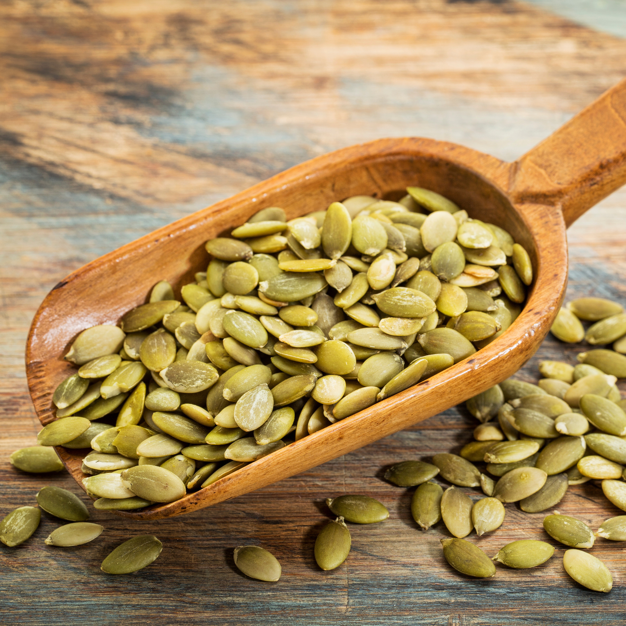 Person holding green capsules with pumpkin and berries in foreground.