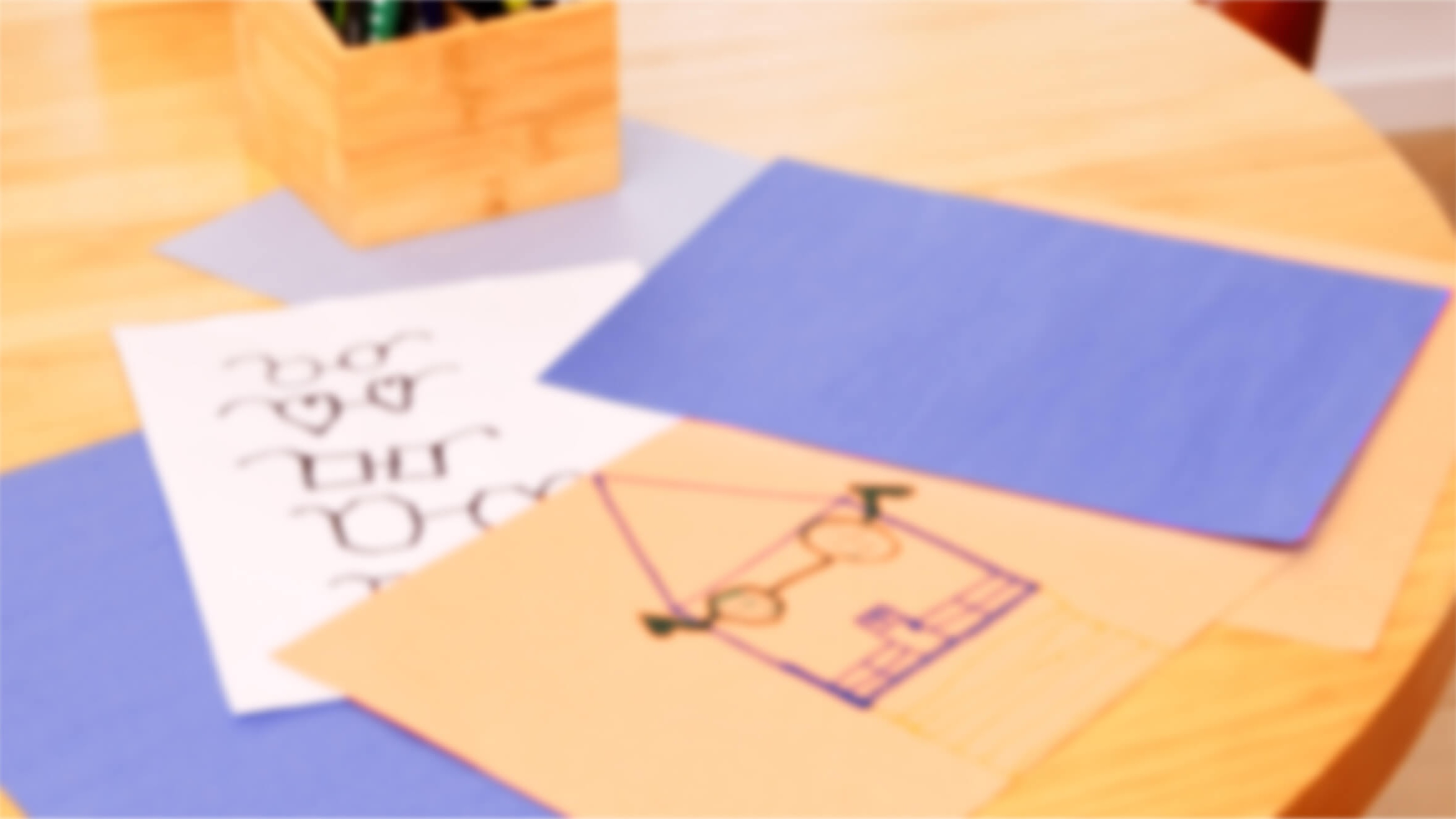 Blurred image of papers and a wooden pencil holder on a table.